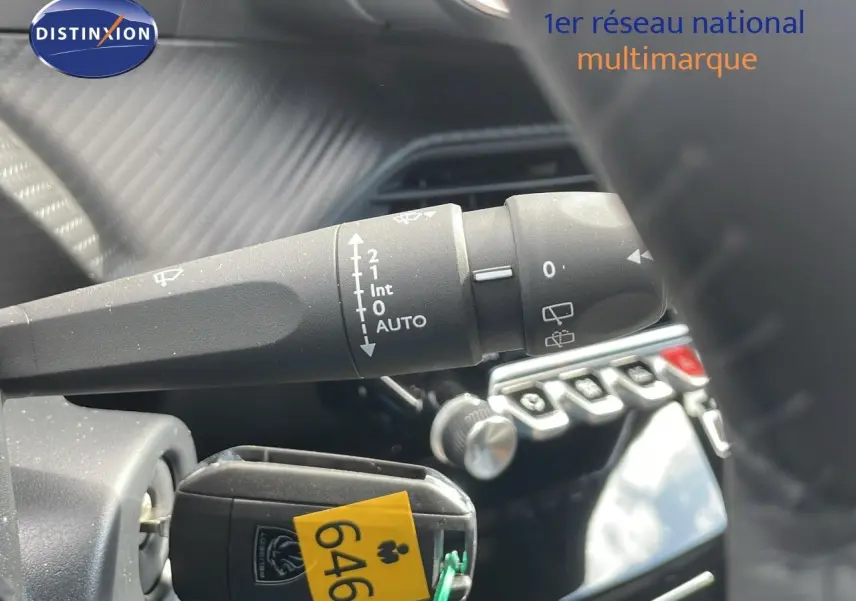 Gros plan sur la commande d'essuie-glace et la clé Peugeot dans l'habitacle noir du 2008 2025.