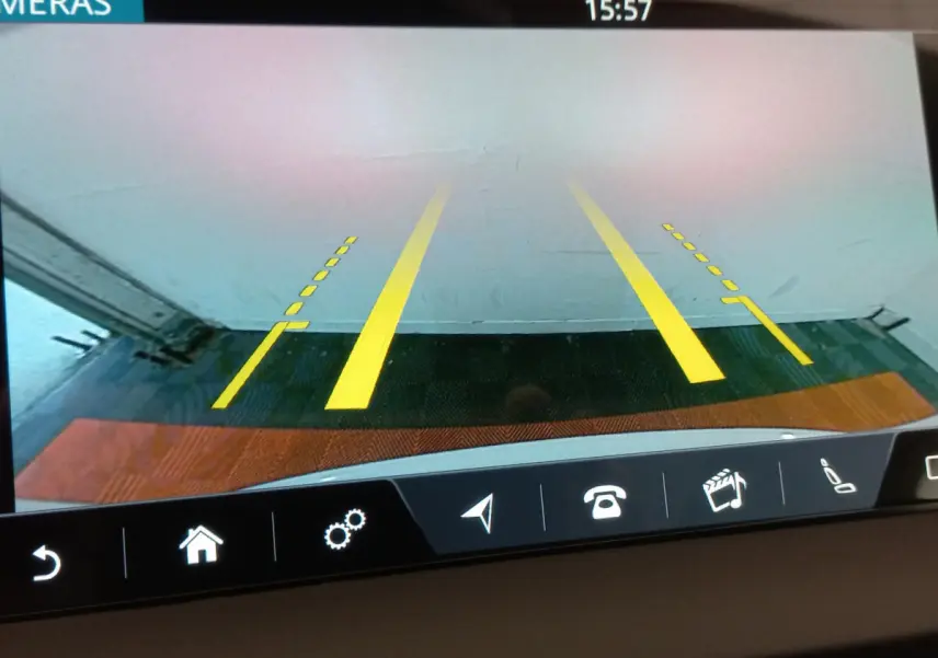 Vue de la caméra de recul du Jaguar E-PACE blanc, affichant les lignes de guidage jaunes sur un sol carrelé.
