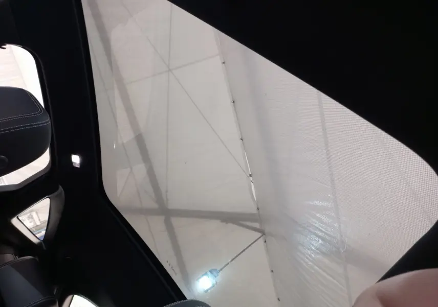 Toit panoramique en verre de l'intérieur d'un Jaguar E-PACE blanc, vue vers le ciel depuis l'arrière