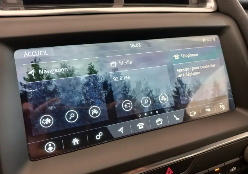 Écran tactile central du tableau de bord du Jaguar E-PACE blanc, affichant navigation et média à 16h03.