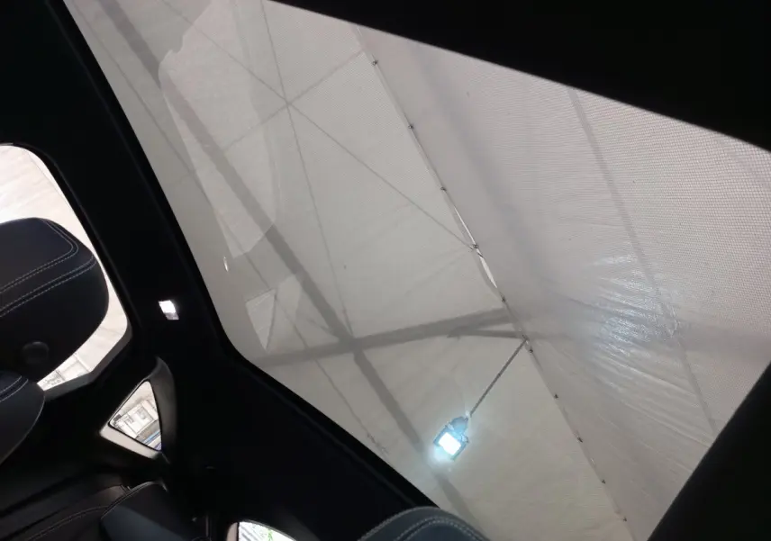 Toit panoramique en verre vu de l'intérieur arrière gauche du Jaguar E-PACE blanc 2019 avec ciel couvert.