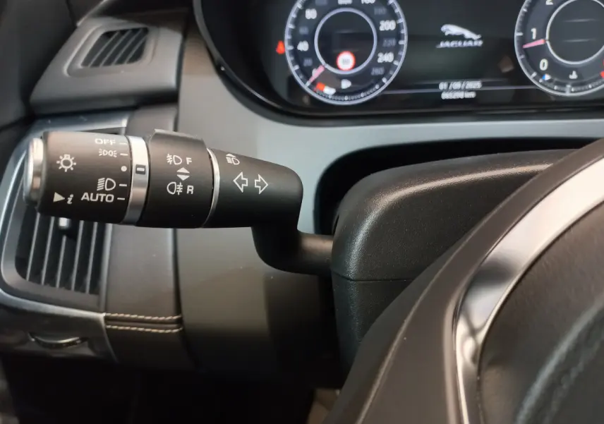 Gros plan sur la manette de clignotants noire à gauche du volant cuir du tableau de bord du Jaguar E-PACE blanc 2019.