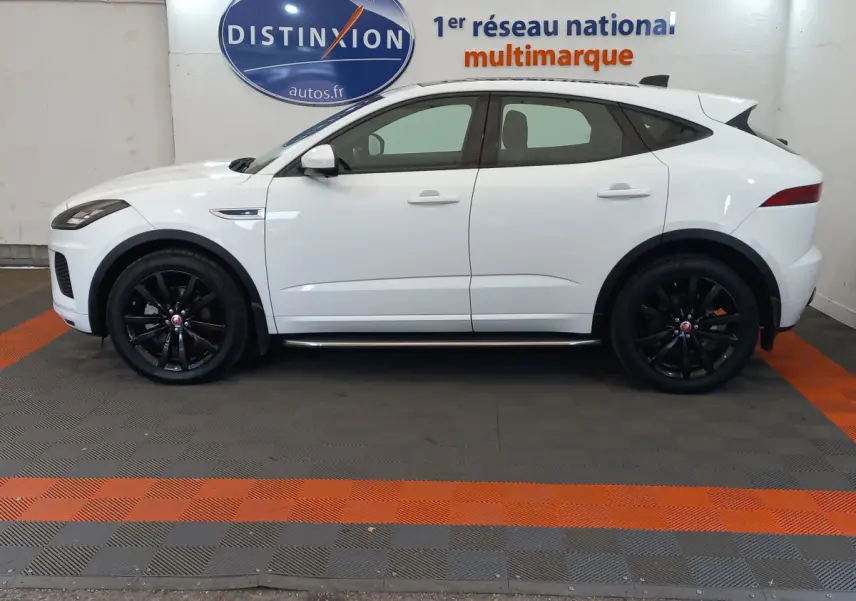 Profil côté gauche d'un Jaguar E-PACE blanc 2019 avec jantes noires et lignes sportives marquées.