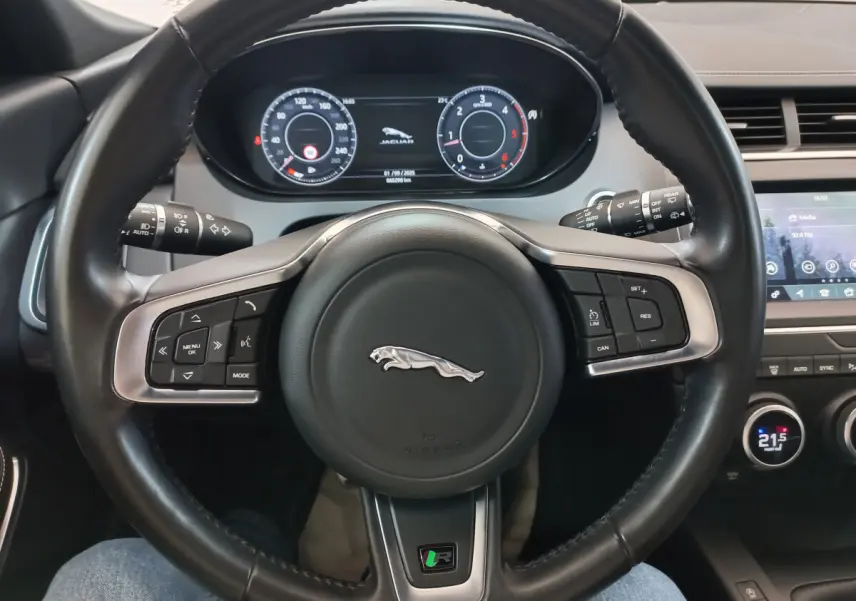 Vue rapprochée du volant cuir noir d'une Jaguar E-PACE 2019 avec tableau de bord digital et écran tactile central.