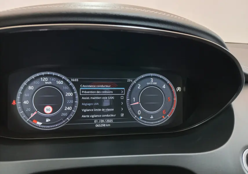 Tableau de bord numérique de Jaguar E-PACE blanc, affichant les aides à la conduite et compteurs ronds lumineux.
