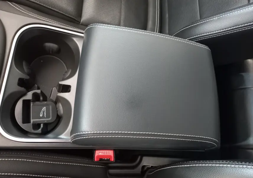 Gros plan sur l'accoudoir central en cuir noir avec surpiqûres blanches et porte-gobelets du Jaguar E-PACE blanc 2019.