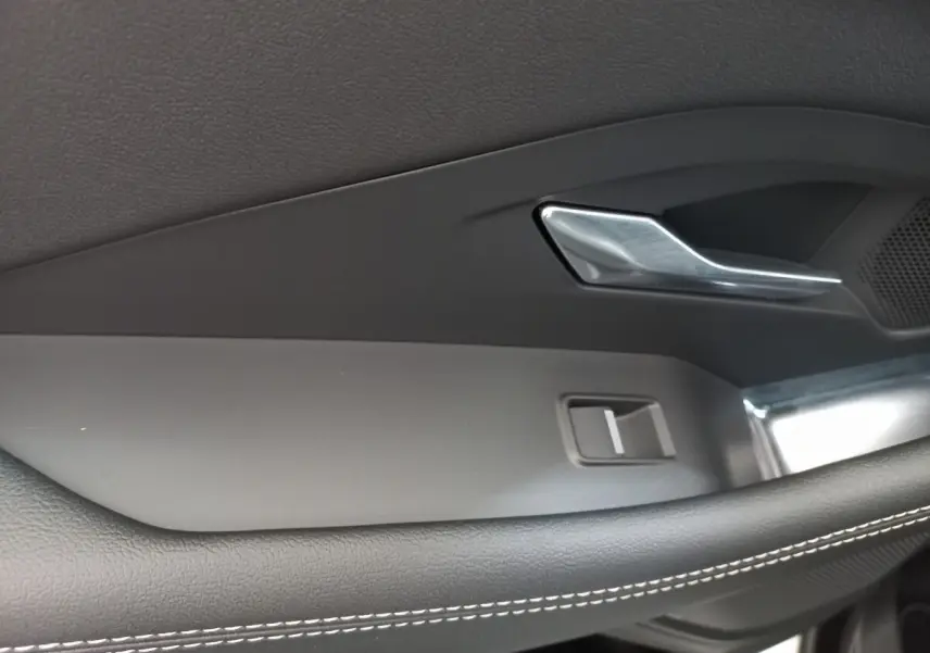 Poignée de porte intérieure côté gauche de la Jaguar E-PACE blanc, avec surpiqûres blanches et insert métal brossé.