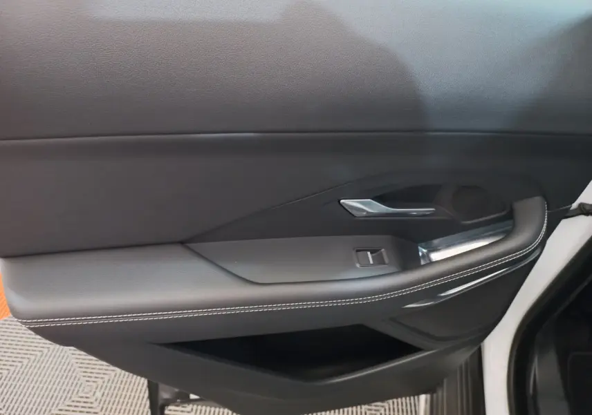 Gros plan sur la porte intérieure côté droit d'une Jaguar E-PACE blanche avec garniture noire et surpiqûres blanches.