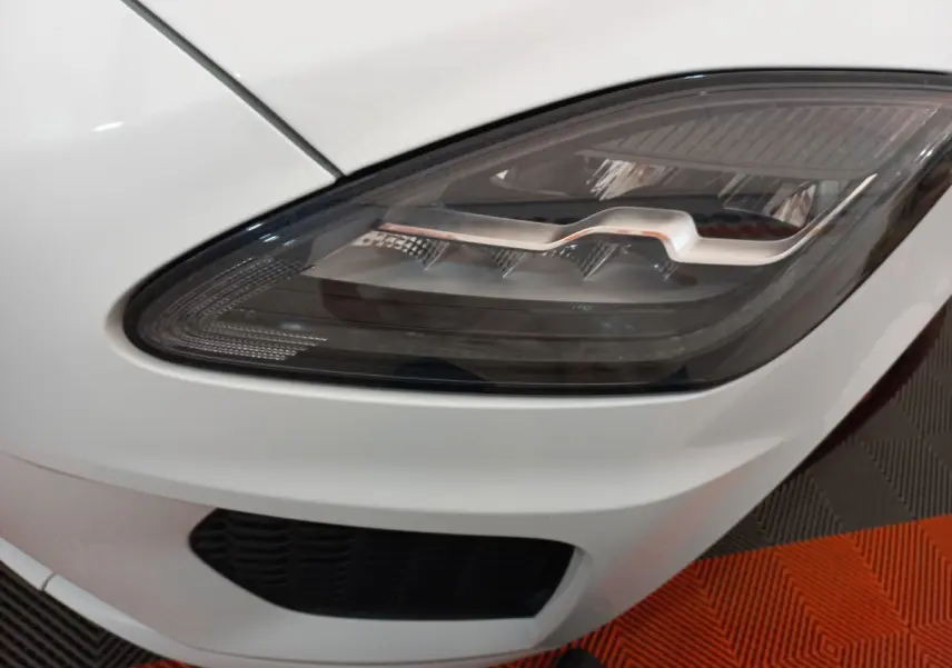 Gros plan sur le phare avant droit du Jaguar E-PACE blanc, soulignant son design LED distinctif.
