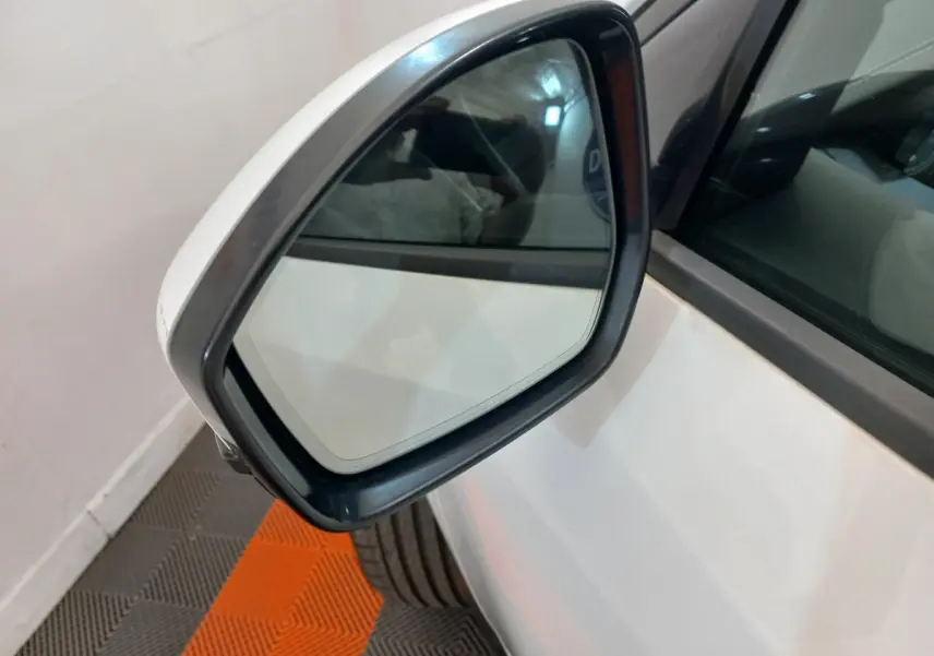 Rétroviseur extérieur côté gauche blanc d'un Jaguar E-PACE 2019 avec carrosserie blanche visible en arrière-plan.