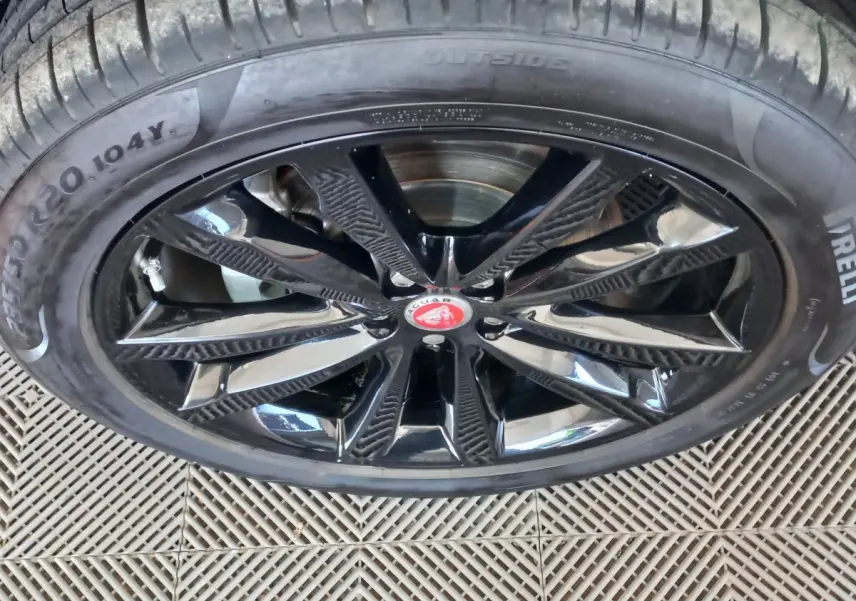Gros plan sur la jante noire brillante avec logo Jaguar rouge au centre du SUV blanc Jaguar E-PACE 2019.
