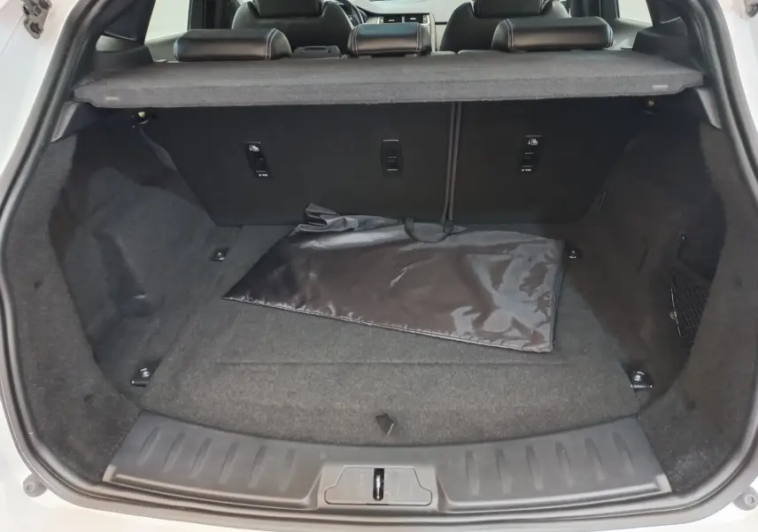 Coffre ouvert vu de l'arrière d'un Jaguar E-PACE blanc 2019, avec tapis noir et banquette arrière visible.