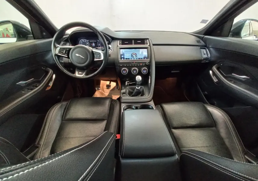 Intérieur noir du Jaguar E-PACE 2019 vu de face, avec volant cuir, tableau de bord digital et boîte manuelle.