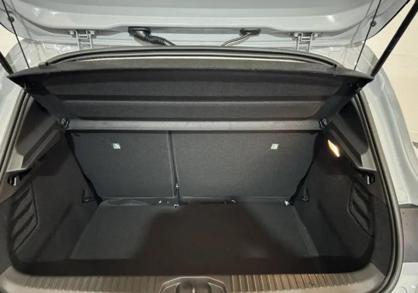 Coffre ouvert vu de l'arrière d'une Renault Clio gris clair, montrant l'espace de chargement vide et la tablette cache-bagages.