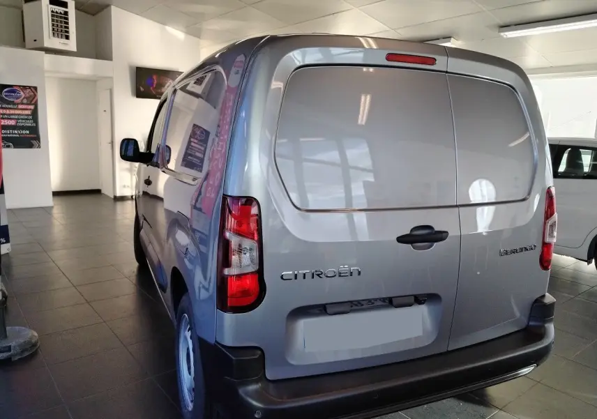 Vue 3/4 arrière droite d'un Citroën Berlingo Van gris acier avec portes arrière pleines dans un showroom.