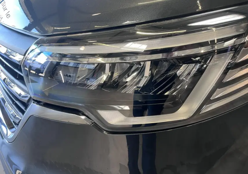 Gros plan sur le phare avant droit du Renault Trafic Fourgon gris foncé, avec calandre et détails LED visibles.