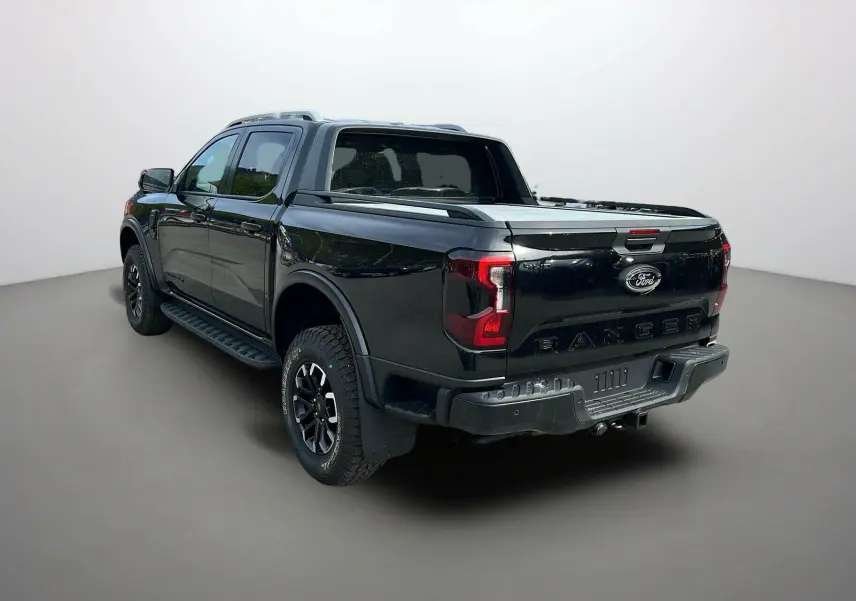 Ford Ranger 2026 noir agate, vue 3/4 arrière droit, avec ridelles, barres de toit et jantes alu noires.