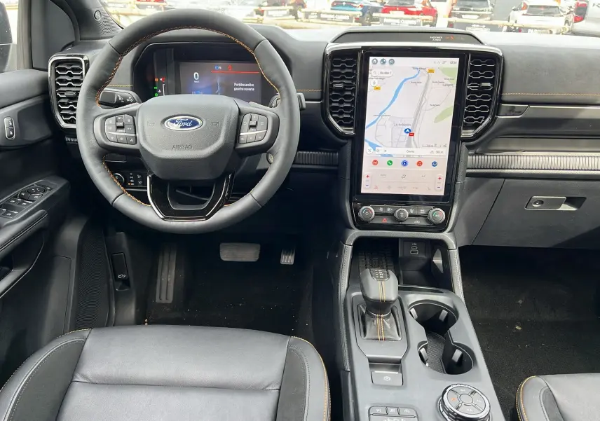 Vue intérieure avant du Ford Ranger 2026 noir agate, volant cuir, écran tactile vertical et levier de vitesses automatique.