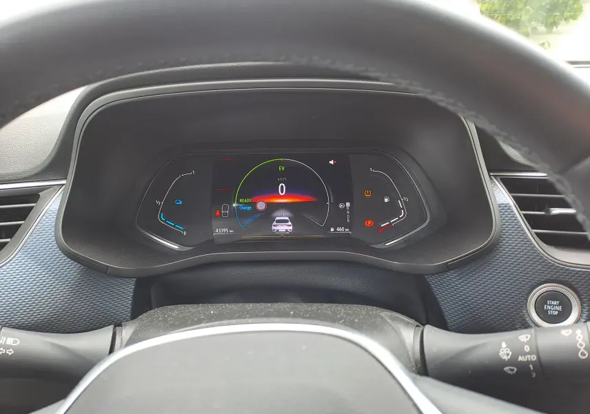 Tableau de bord numérique vu de face dans un Renault Arkana 2023, affichant 0 km/h et indicateurs hybrides.