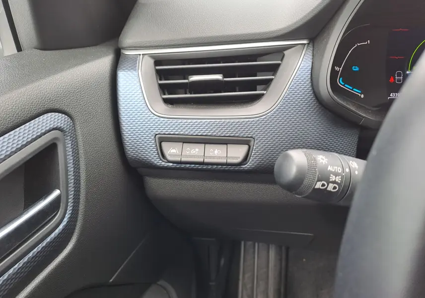Détail de la console gauche avec aérateur et commandes d'assistance sur fond bleu Zanzibar métal dans un Renault Arkana hybride 2023.