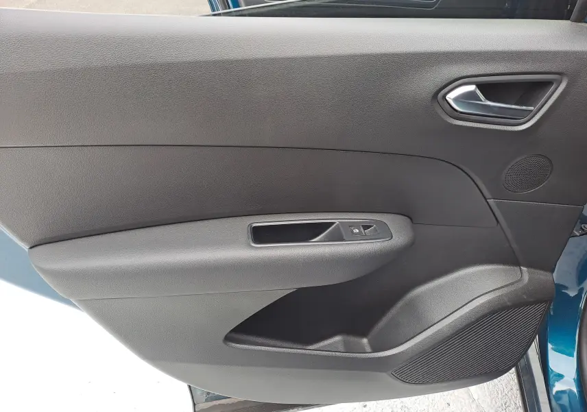 Intérieur côté gauche de la porte avant du Renault Arkana bleu Zanzibar, avec poignée argentée et commande de vitre.