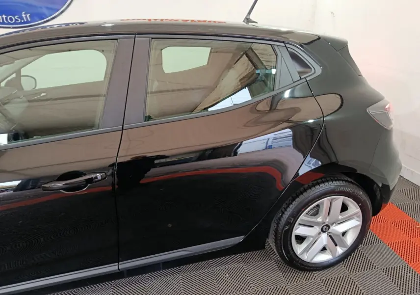 Vue latérale droite d'une Renault Clio noire brillante, mettant en valeur la porte arrière et la roue arrière en alliage.