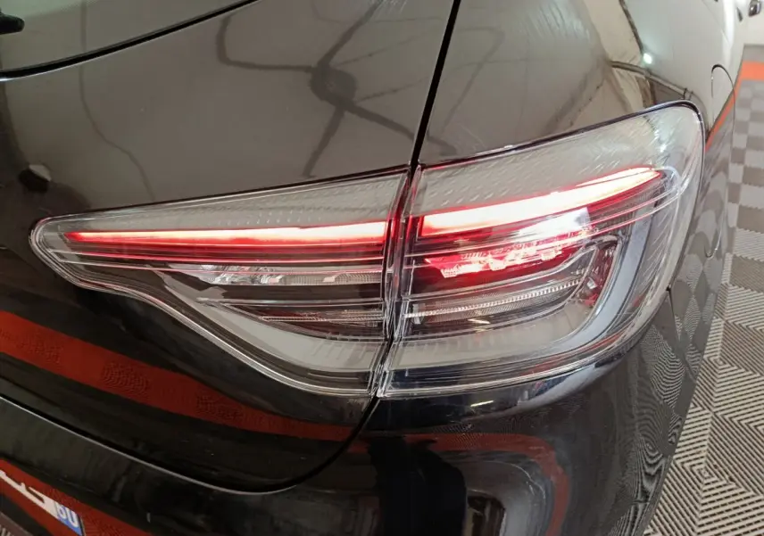 Gros plan sur le feu arrière droit rouge et blanc d'une Renault Clio noire Evolution Blue dCi 100 -25 2025.
