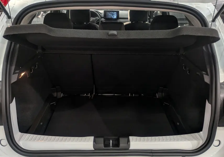 Vue depuis le coffre ouvert d'une Dacia Sandero Stepway blanc glacier, montrant l'espace de chargement et l'intérieur noir.