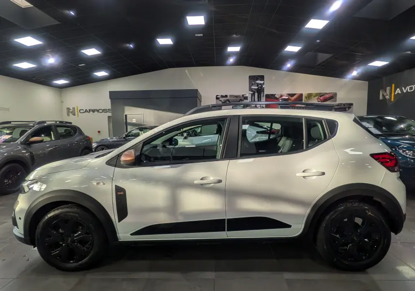 Profil côté gauche d'une Dacia Sandero Stepway TCe 110 blanche Glacier avec jantes noires et détails noirs contrastants.