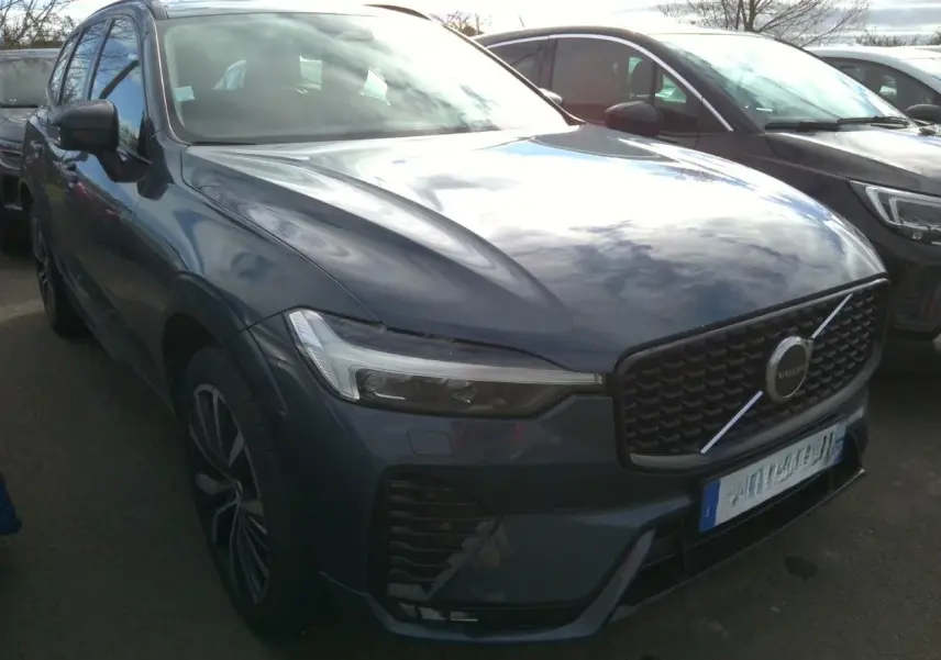 Vue 3/4 avant droite d'un Volvo XC60 bleu avec calandre noire laquée et jantes alliage 20 pouces bicolores.