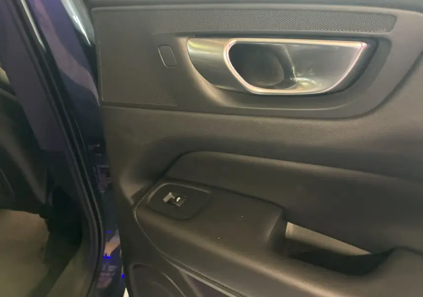 Gros plan sur la poignée intérieure et le panneau de porte côté conducteur du Volvo XC60 bleu 2023.