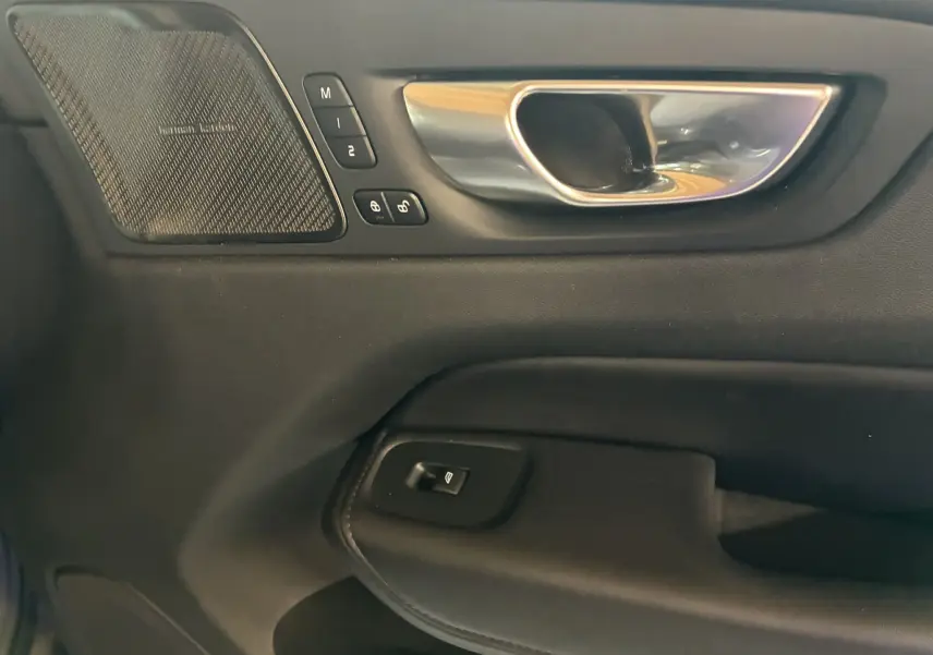Gros plan sur la poignée intérieure côté conducteur du Volvo XC60 2023 avec haut-parleur Harman Kardon et commandes mémoire sièges.
