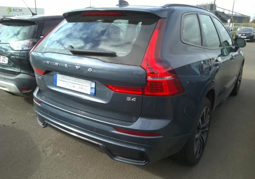 Volvo XC60 bleu vue 3/4 avant droit, calandre noire laquée et jantes alliage 20 pouces en Y noir/diamant.