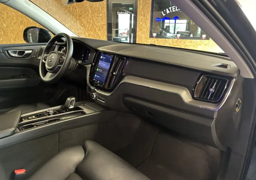 Intérieur noir du Volvo XC60 2023 vu côté passager, avec tableau de bord moderne et écran tactile central.