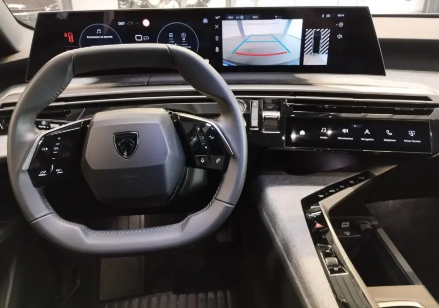 Vue intérieure centrée sur le volant et le tableau de bord avec écran incurvé du Peugeot 3008 gris Artense 2024.