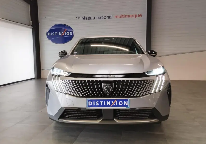 Vue frontale du Peugeot 3008 gris Artense avec calandre distinctive et feux LED en griffes allumés.