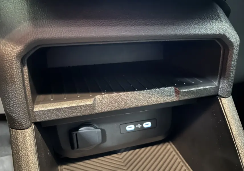 Prise USB double et prise 12V sous le tableau de bord du Dacia Duster 2024, intérieur noir.