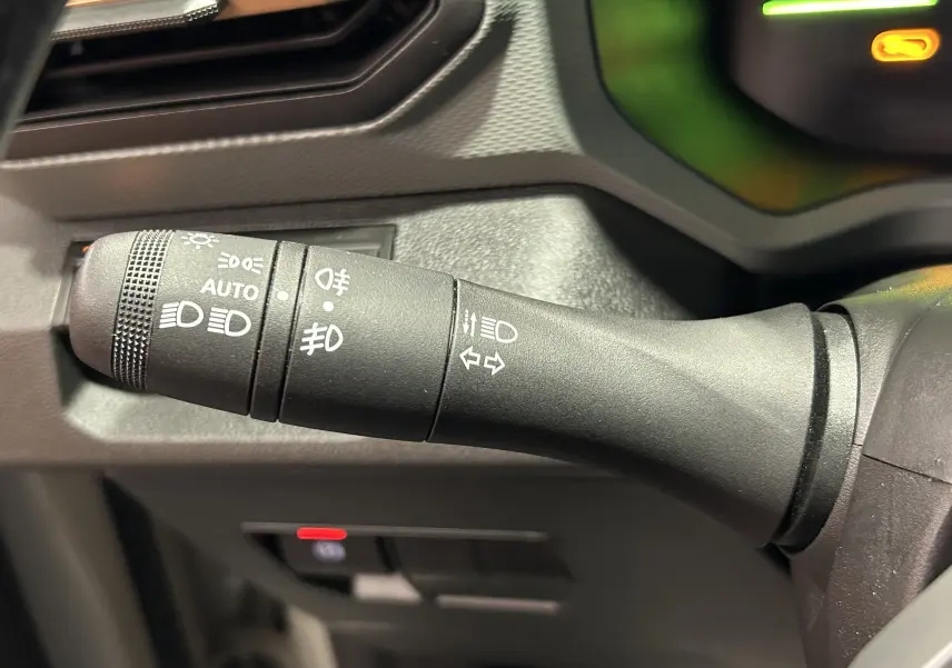 Gros plan sur la commande des feux et clignotants du Dacia Duster 2024, détails en plastique noir mat.