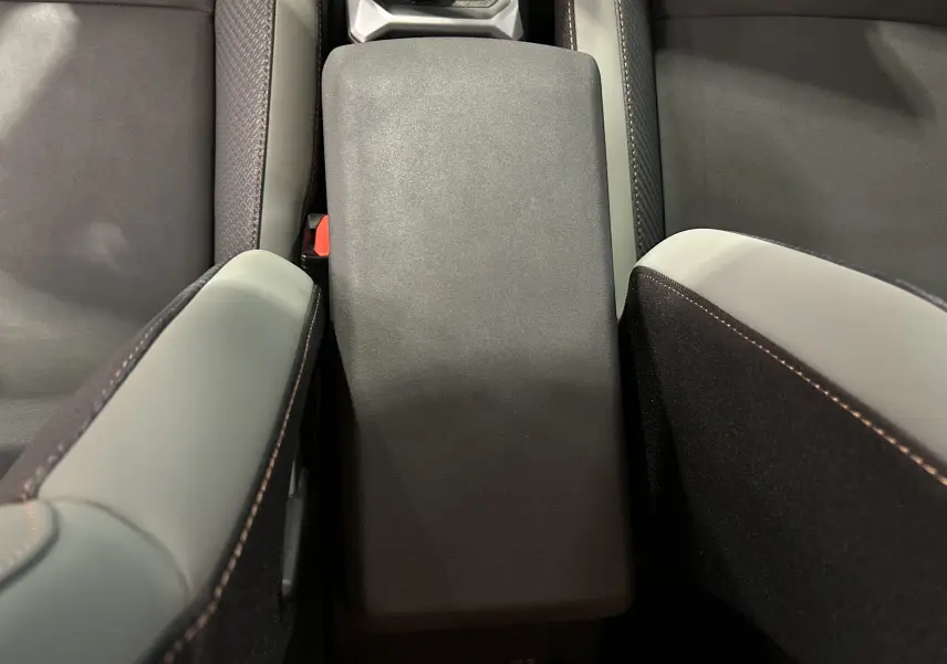 Vue rapprochée de l'accoudoir central et des sièges gris clair et noir du Dacia Duster 2024, version TCE 130 4x4.