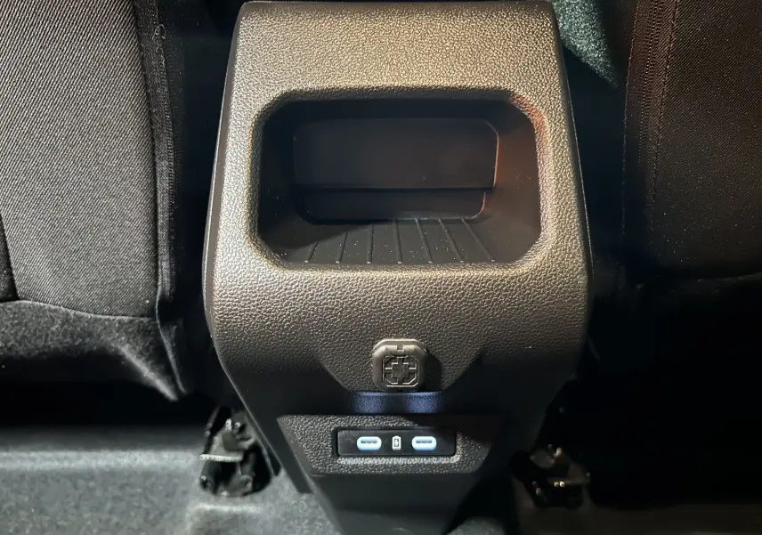 Gros plan sur la console arrière noire du Dacia Duster 2024 avec prises USB-C et rangement intégré.