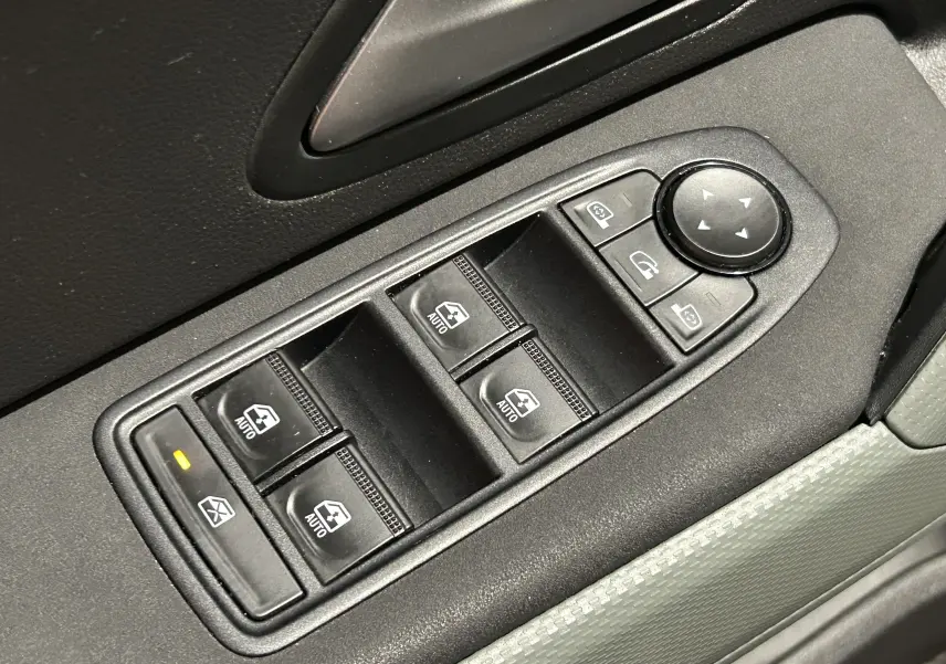 Gros plan sur les commandes électriques des vitres et rétroviseurs côté conducteur du Dacia Duster 2024 couleur Sandstone.