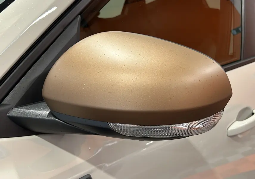 Gros plan sur le rétroviseur côté gauche couleur Sandstone du Dacia Duster 2024 avec clignotant intégré.