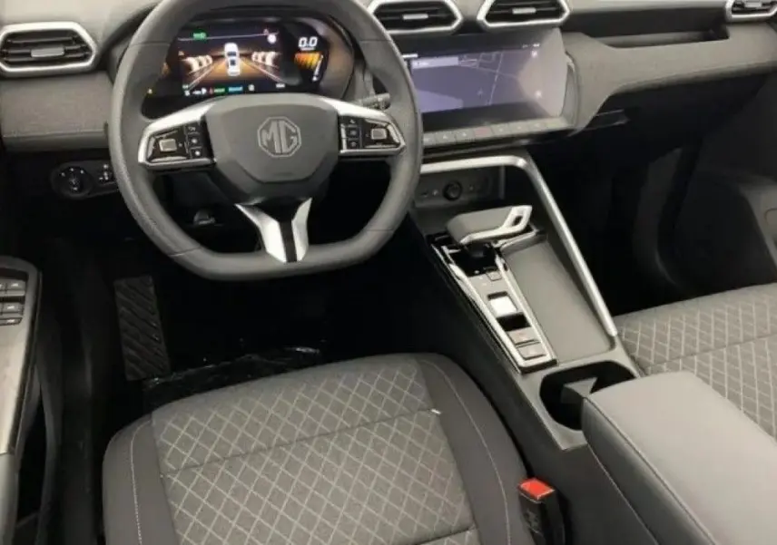 Vue intérieure avant du MG ZS 2026 avec volant multifonction, tableau de bord digital et sièges tissu gris à motifs.
