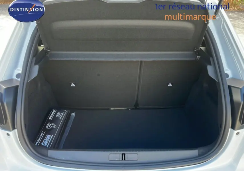 Coffre ouvert d’une Peugeot 208 Hybrid blanc Okenite, vue arrière montrant un espace de rangement propre et spacieux.