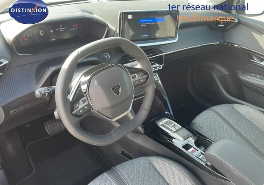 Vue intérieure avant droite du Peugeot 208 Hybrid blanc, avec volant compact et écran tactile central lumineux.