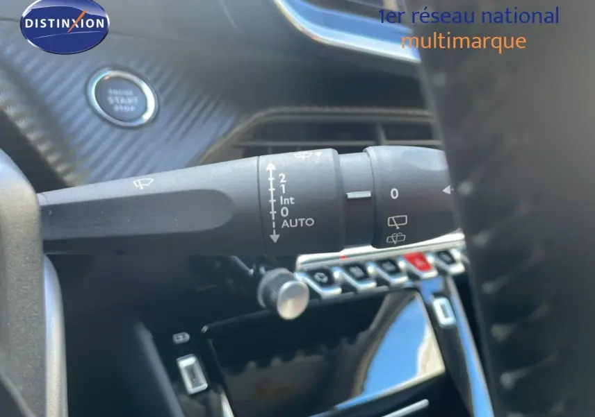 Gros plan sur la commande d’essuie-glace et le bouton start/stop du tableau de bord d’une Peugeot 208 blanche.