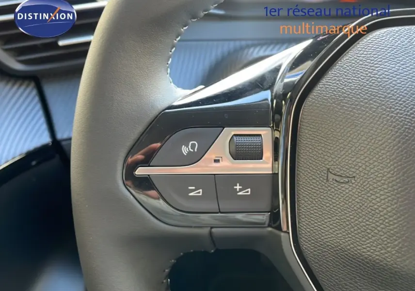Gros plan sur les commandes gauche du volant cuir noir d’une Peugeot 208 Hybrid blanche, avec boutons de volume et de commande vocale.