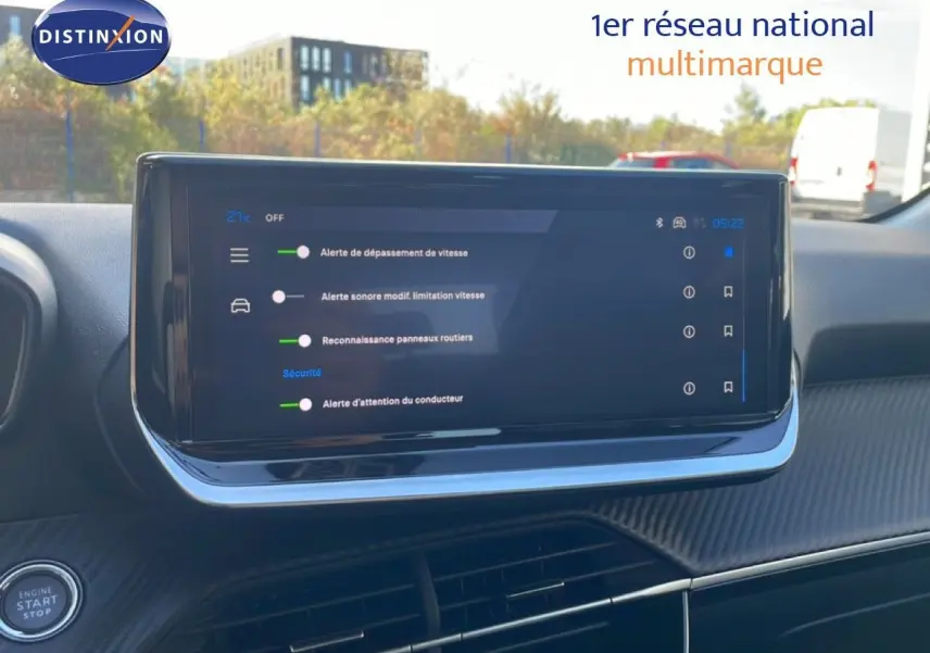 Vue intérieure du tableau de bord de la Peugeot 208 blanche, écran tactile affichant les alertes de sécurité.