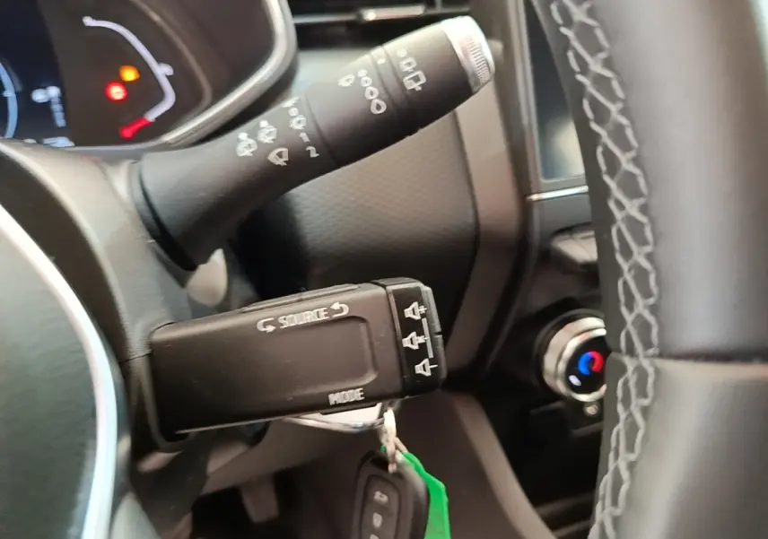 Gros plan sur la commande multifonctions et partie du volant en cuir synthétique de la Renault Clio Business E-TECH 140 blanche.