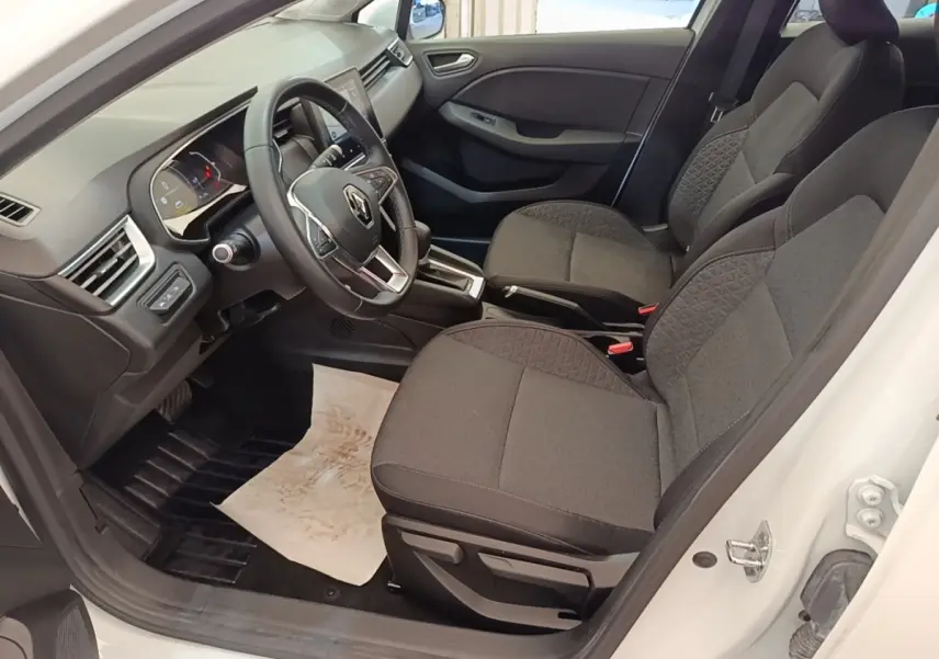 Vue intérieure côté conducteur de la Renault Clio Business E-TECH blanche, avec sièges gris et volant multifonctions en cuir synthétique.